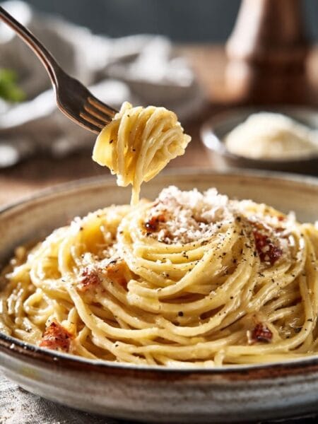 Classic spaghetti carbonara with pancetta, black pepper, and grated cheese served in a ceramic bowl