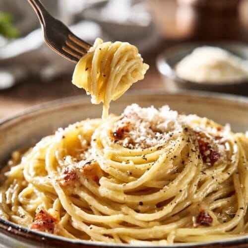 Classic spaghetti carbonara with pancetta, black pepper, and grated cheese served in a ceramic bowl